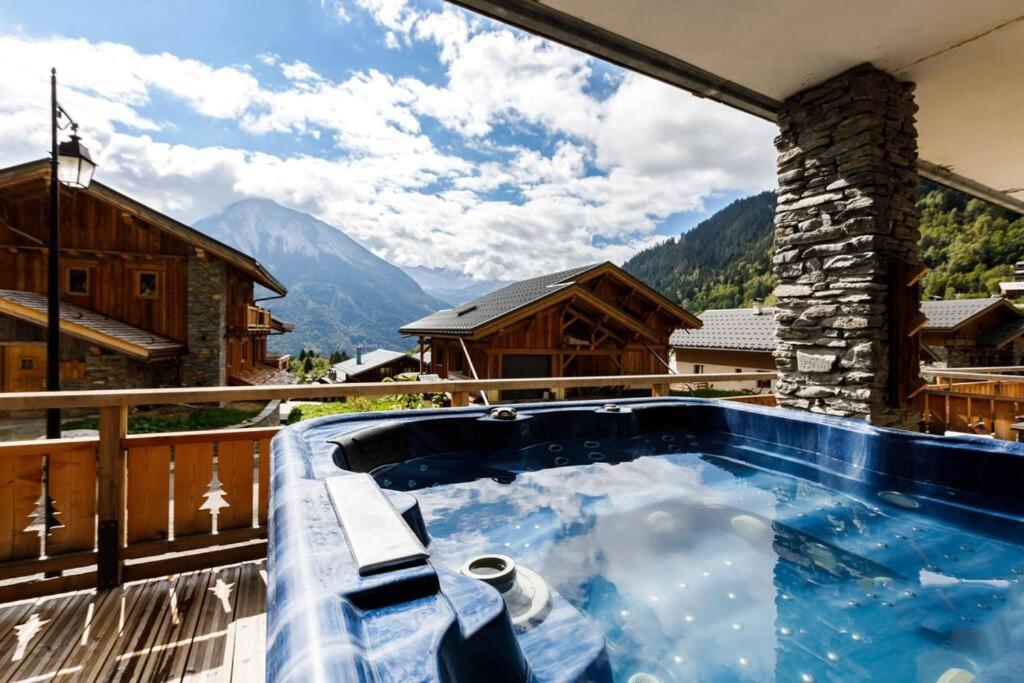 a hot tub on a balcony with a view of mountains at Superbe logement, jacuzzi extérieur, vue, sauna in Champagny-en-Vanoise