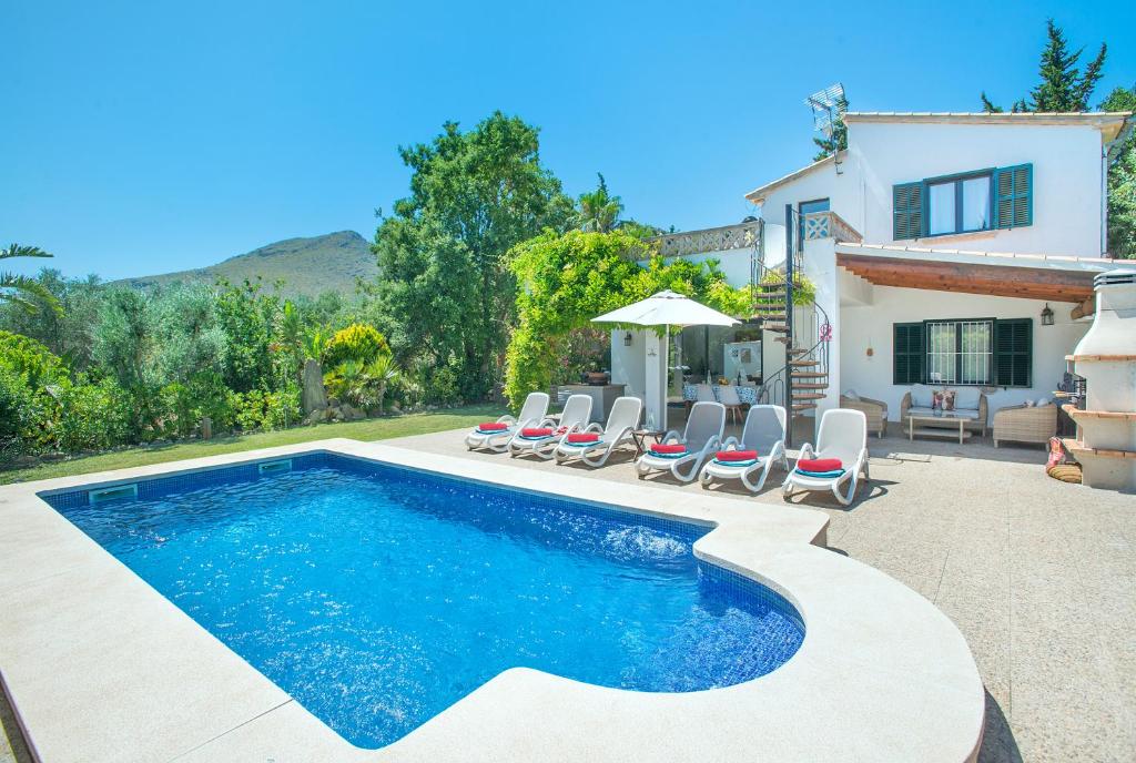 a swimming pool with chairs and a house at Owl Booking Villa Bocoris - 15 Min Walk to the Beach in Port de Pollensa