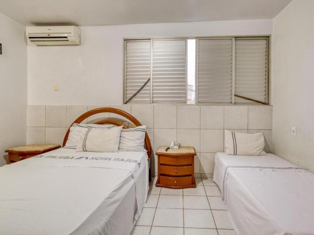 a bedroom with two beds and a window at Itajubá Classic Hotel Goiânia in Goiânia