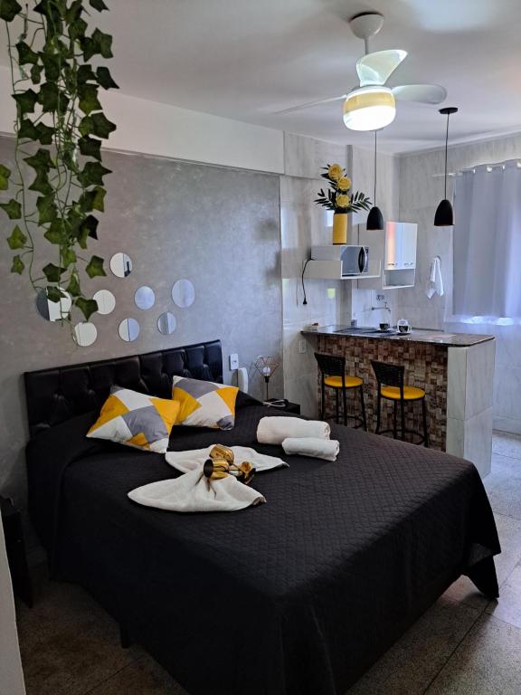 a bedroom with a black bed and a kitchen at Apartamento CondominioEuropa centro de barra mansa in Barra Mansa