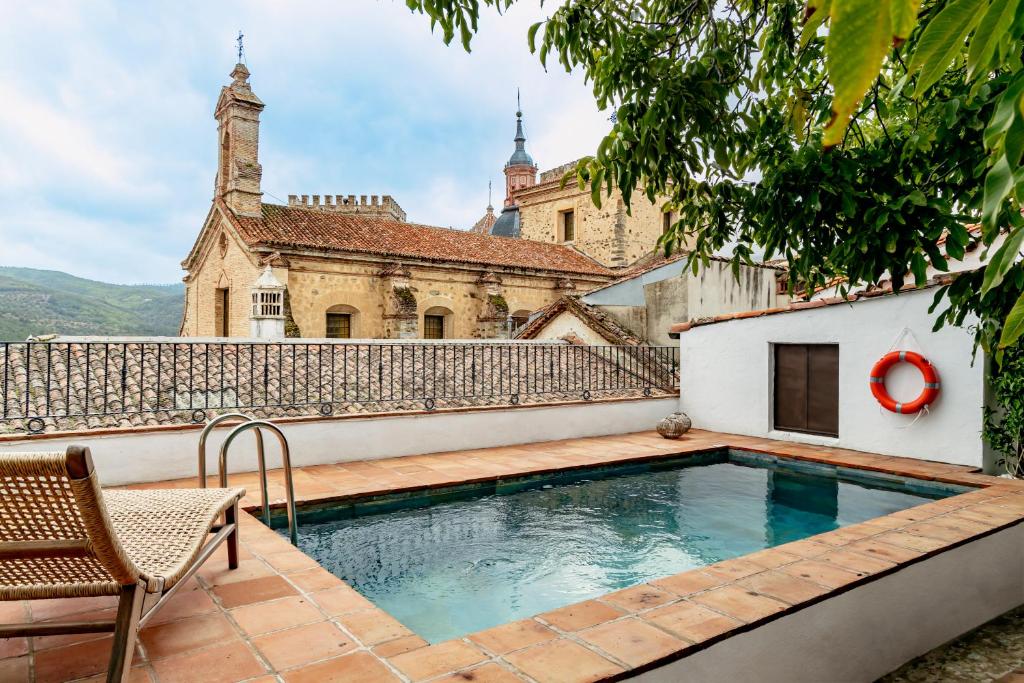 an old house with a swimming pool in front of a building at Apartamentos turísticos EL PATIO DEL NOGAL in Guadalupe
