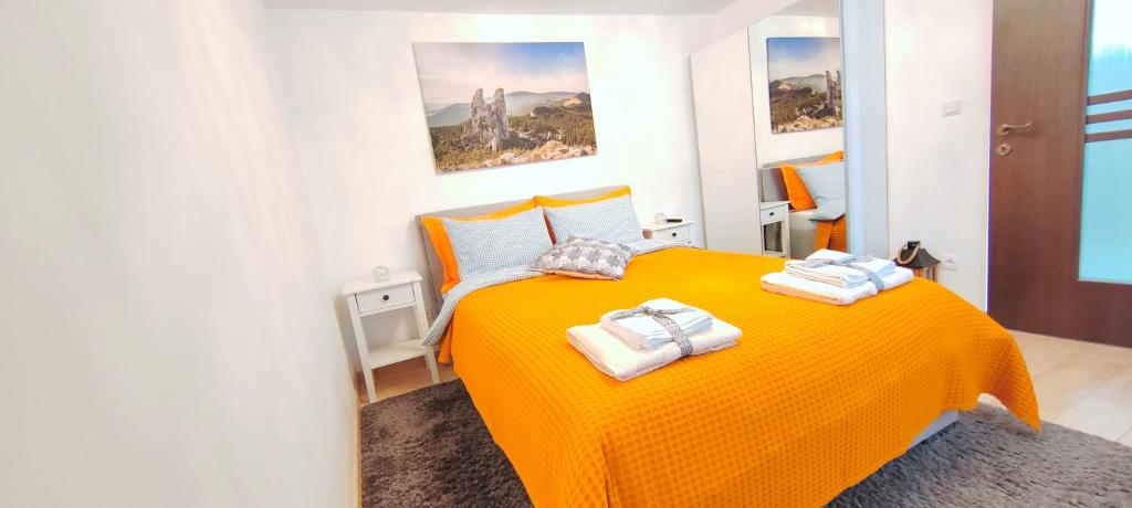 a bedroom with an orange bed with towels on it at R&B Guest House in Câmpulung Moldovenesc