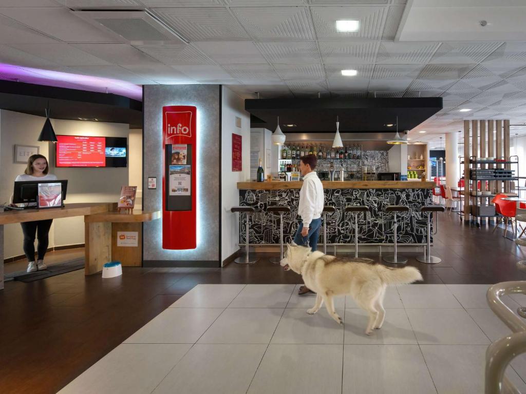 ein Hund, der mit einer Person und einer Bar durch ein Restaurant geht in der Unterkunft ibis Epernay Centre Ville in Épernay