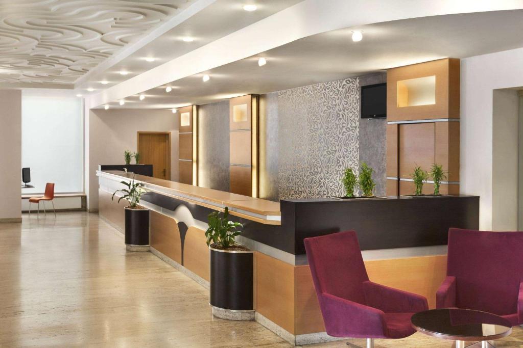 a lobby with a waiting area with purple chairs at Ramada by Wyndham Bucharest Parc Hotel in Bucharest
