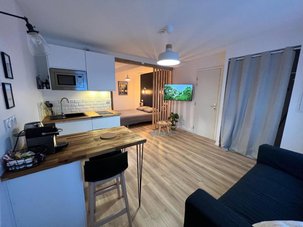 een keuken en een woonkamer met een tafel en een bank bij Studio 1 - Mi-Côte - Studio à Orvault in Orvault