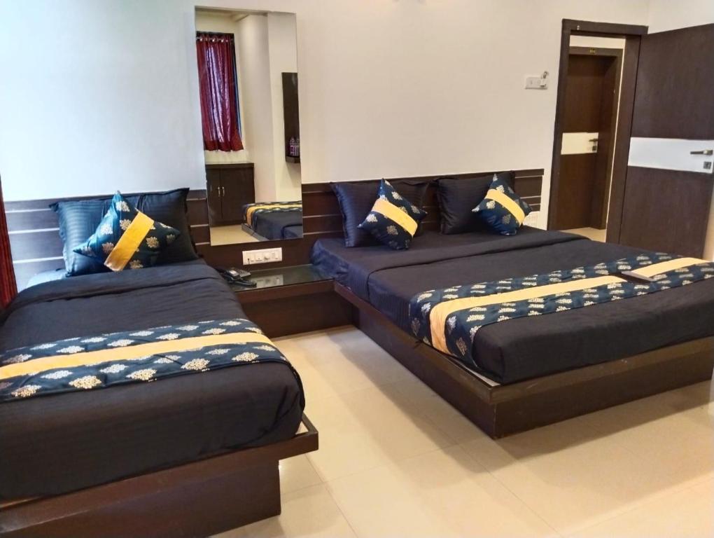 a bedroom with two beds and a mirror at Hotel Shri Govind in Shirdi