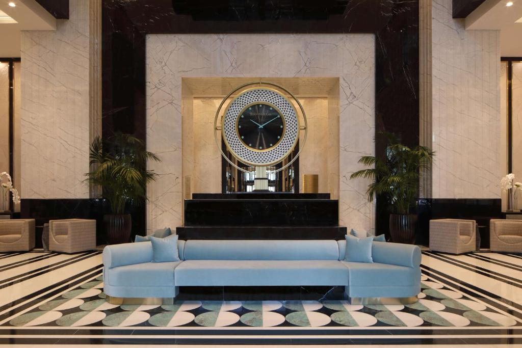 Waldorf Astoria Doha West Bay في الدوحة: كنب ازرق في لوبي مع ساعه