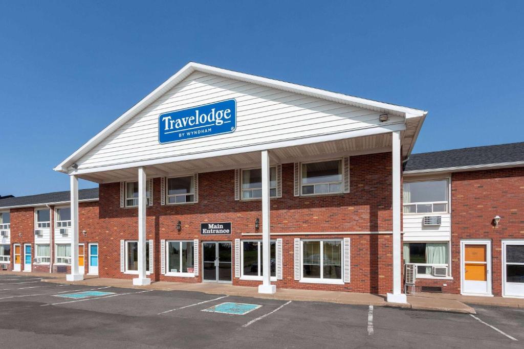 a large red brick building with a sign on it at Travelodge by Wyndham Amherst in Amherst