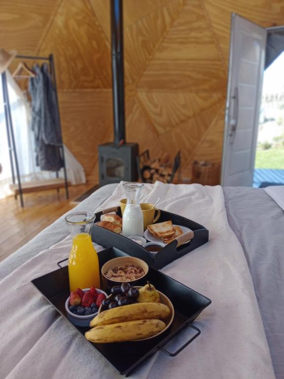 a tray of food with fruit and juice on a bed at Bóreas Ecoluxury Glamping in El Calafate