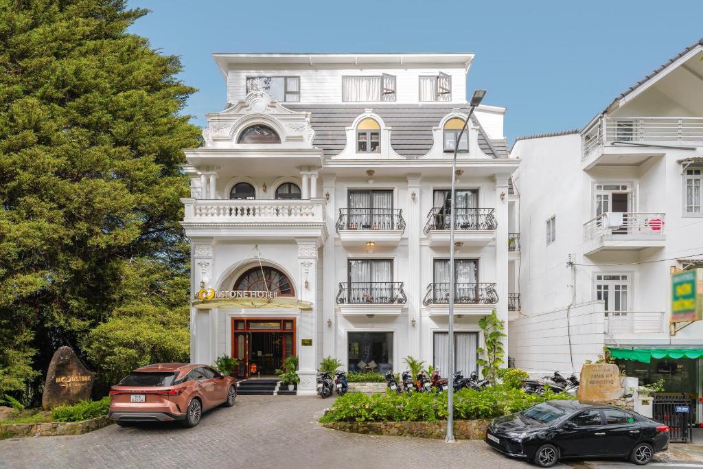 un edificio blanco con coches estacionados frente a él en TTR Moonstone Apart Hotel en Da Lat