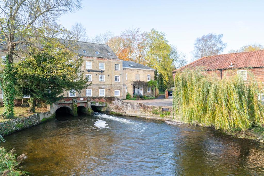 a river in a town with a bridge and buildings at The Old Mill Cottage in Fakenham