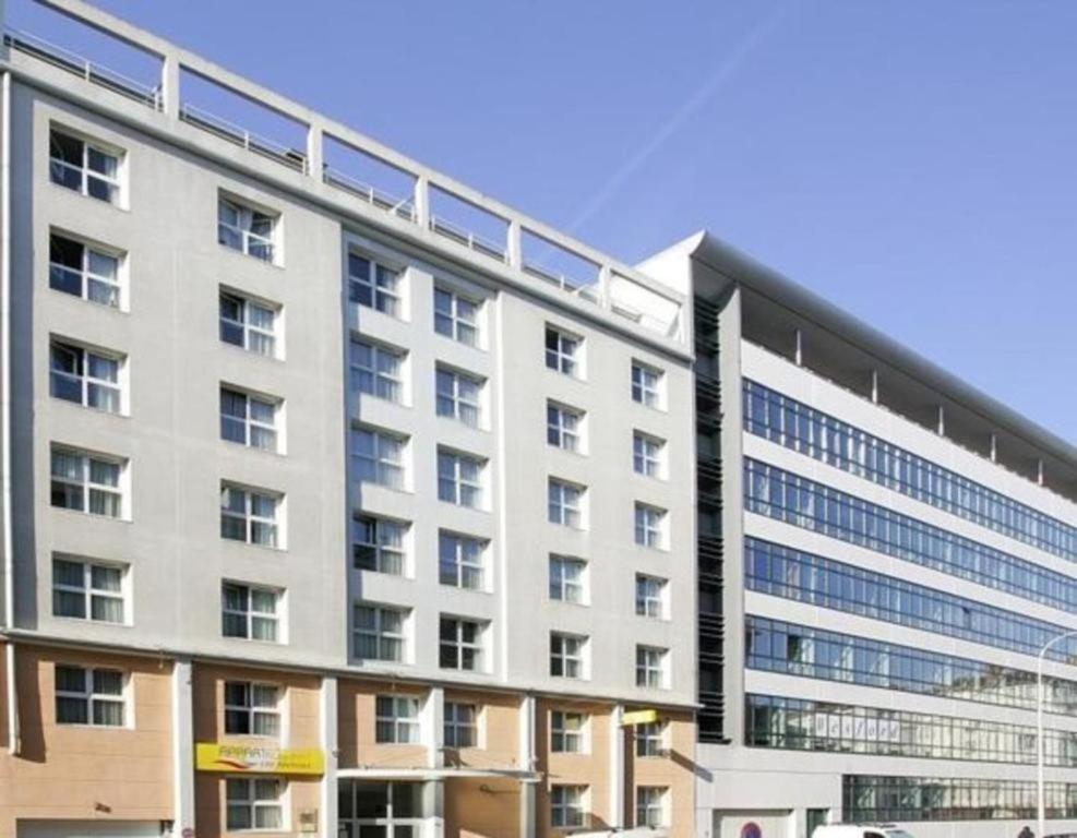 um grande edifício branco com muitas janelas em Appart Suites Citadines Access 15 minutes Paris Montparnasse - Metro & Accès facile Paris Parc Expo em Châtillon