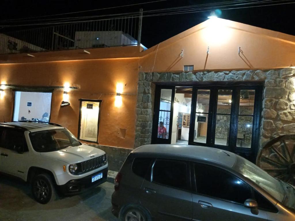 deux voitures garées devant un bâtiment la nuit dans l'établissement Hotel Cactus Plaza, à Purmamarca