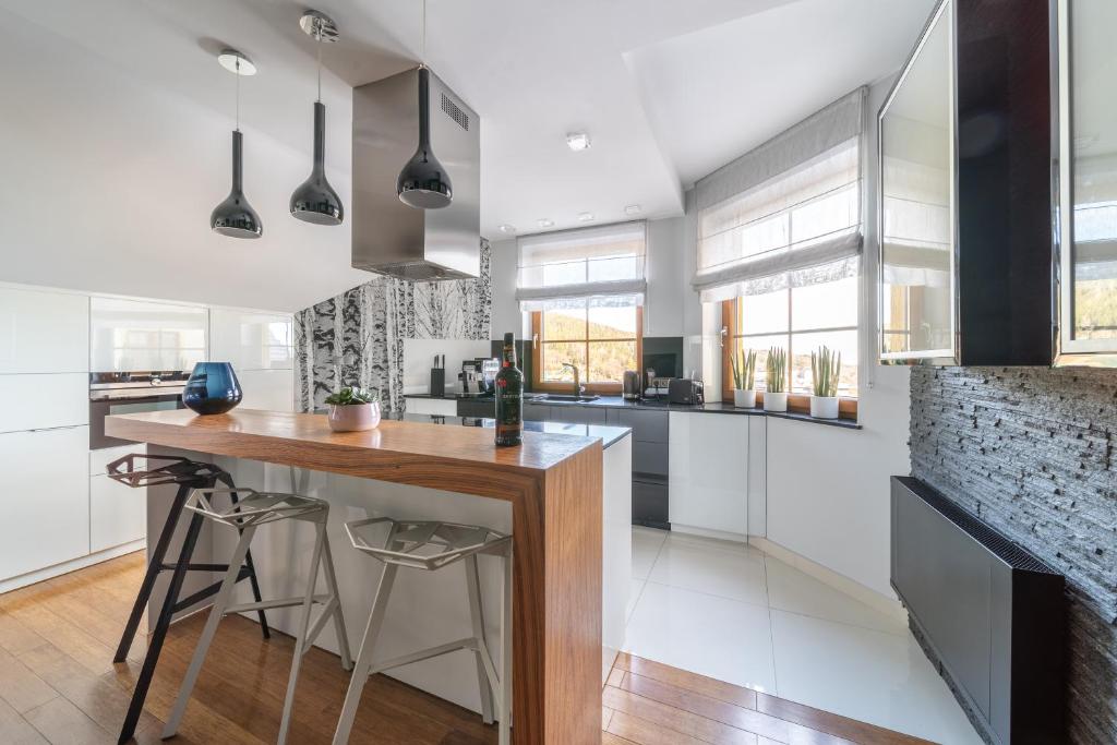 a kitchen with white cabinets and a wooden counter top at Trevilles Apartamenty Mountain View in Szklarska Poręba