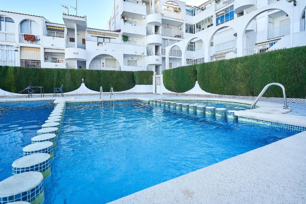 a swimming pool in front of a large building at Espanhouse Magani in Torrevieja