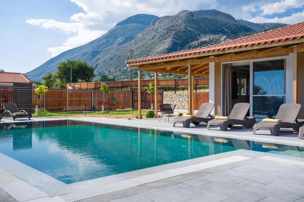 a house with a swimming pool with mountains in the background at Villa Rudi in Atsoupádhes