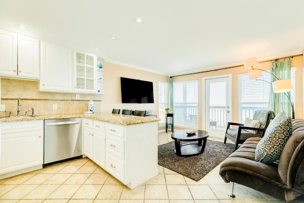 a kitchen with white cabinets and a living room with a couch at Seascape Gem in Galveston