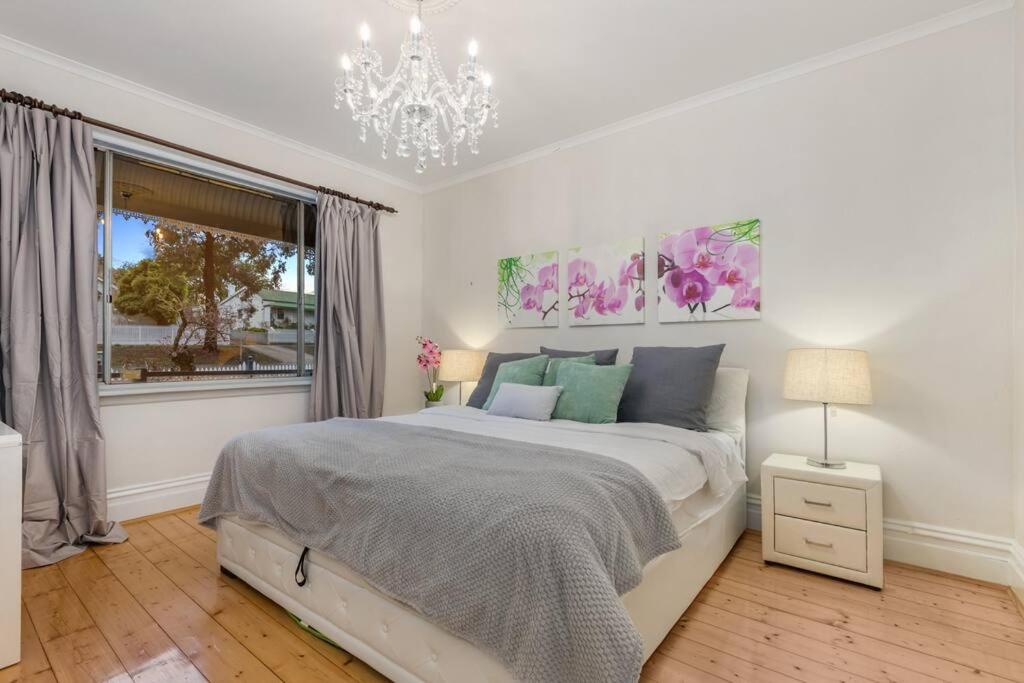 um quarto com uma cama, uma janela e um lustre em Luxury Home Away From Home in Heart Bendigo's CBD em Bendigo