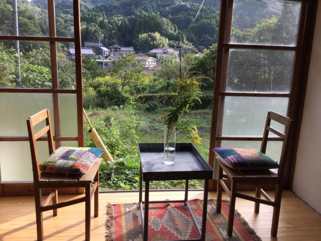 einen Tisch und zwei Stühle vor einem Fenster in der Unterkunft 朝食付き唐津里山の宿&ヨガ兎と亀 in Karatsu