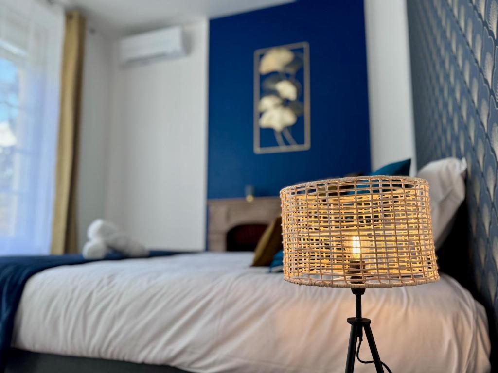 a bedroom with a bed and a rattan lamp at Chaleureux T2 proche gare in Bourgoin