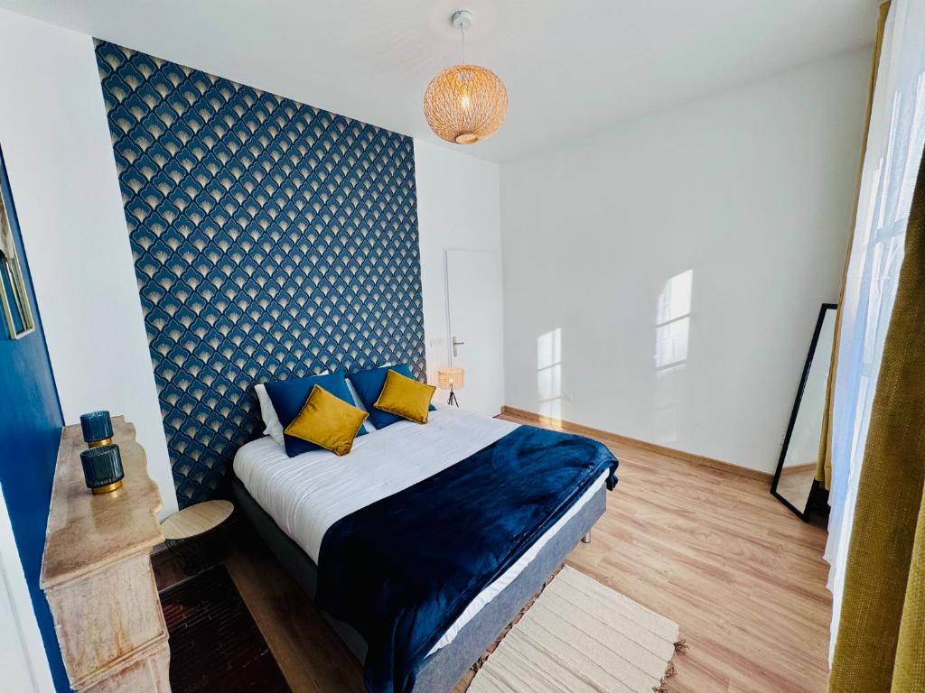 a bedroom with a bed with blue sheets and yellow pillows at Chaleureux T2 proche gare in Bourgoin