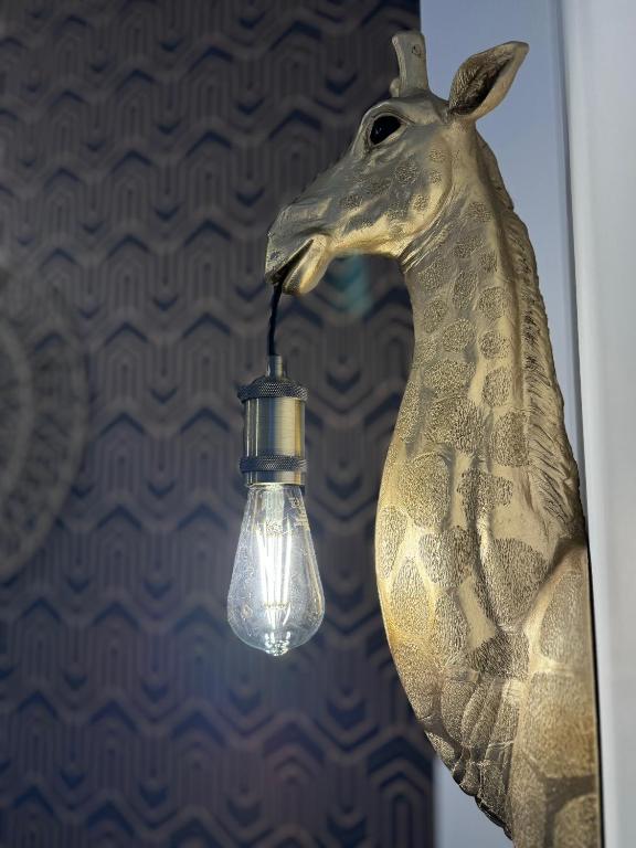 a lamp with a head of a giraffe hanging on a wall at Chaleureux T2 proche gare in Bourgoin