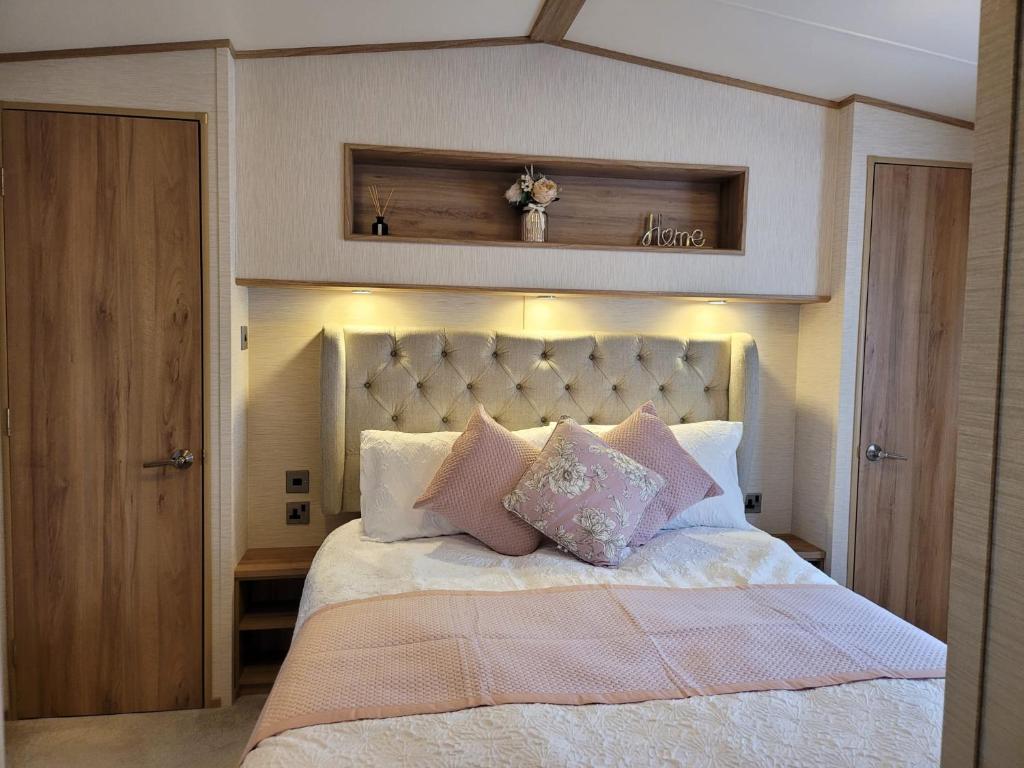 a bedroom with a large bed with pink pillows at New Forest 2-Bed Premium Holiday Home, Hoburne Bashley Holiday Park, New Milton in New Milton