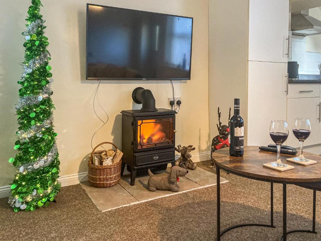 a living room with a stove and a christmas tree at Low Stonebank Cottage-uk41027 in Hunwick