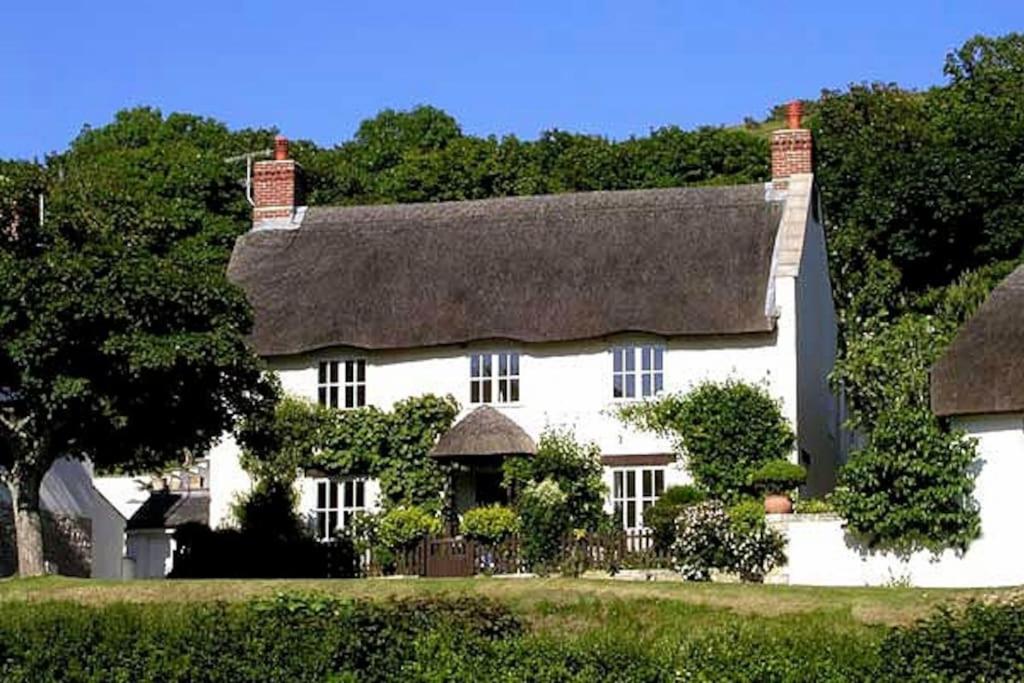 uma grande casa branca com telhado de palha em Spacious Thatched Cottage in West Lulworth, Dorset em West Lulworth