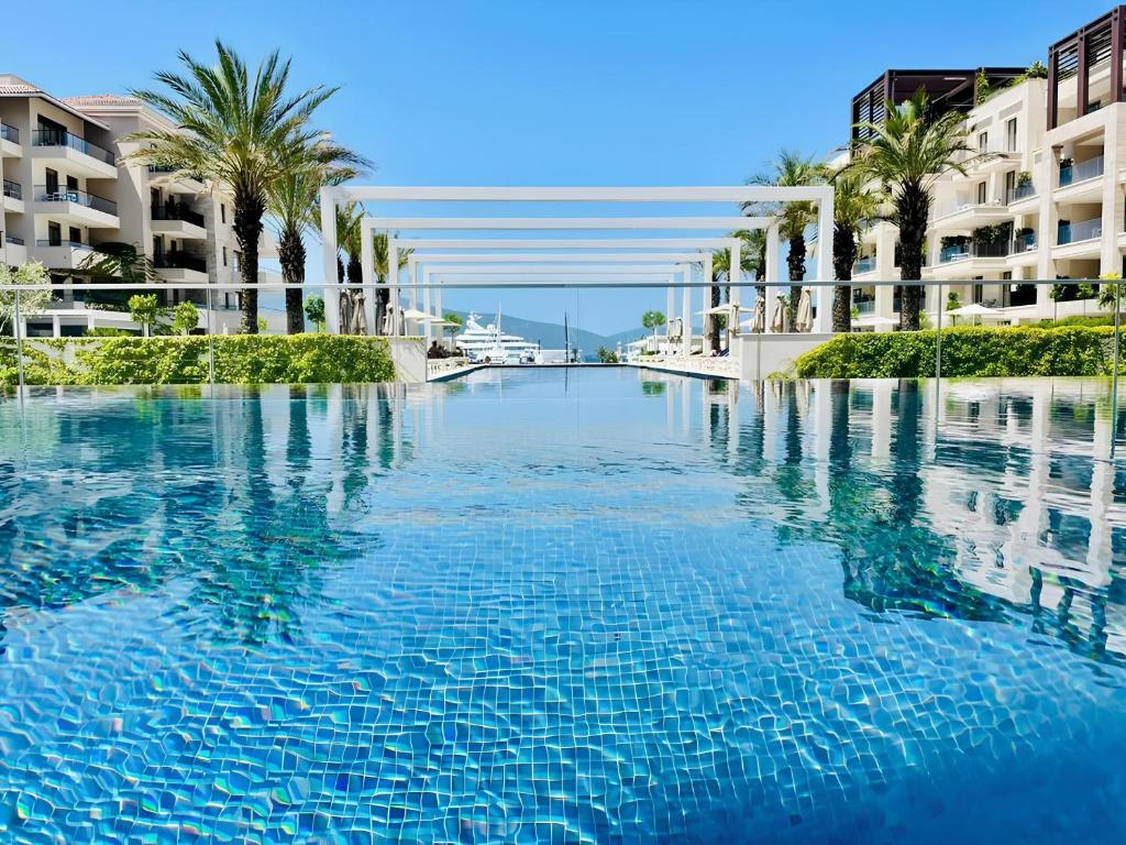 a large pool of blue water with palm trees and buildings at MBroker - Porto Montenegro Elena residence apartments in Tivat