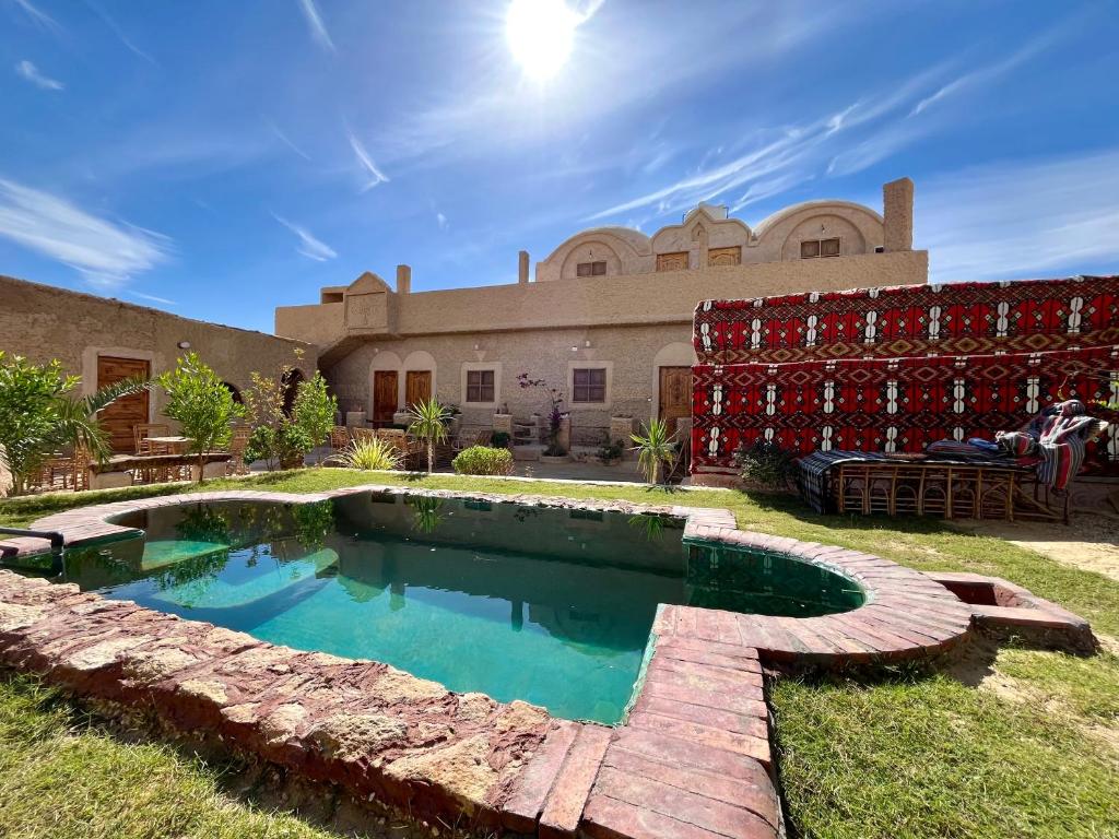 a swimming pool in the yard of a house at Agpeninshal Ecolodge in Siwa