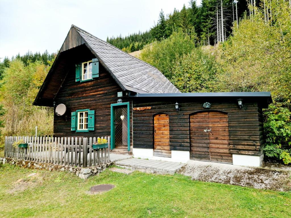 una pequeña casa de madera con una puerta y una valla en Rustic alpine hut in Vordernberg with sauna, en Vordernberg