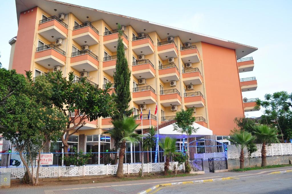 un grande edificio arancione con alberi di fronte di KLEOPATRA SUNLIGHT HOTEL a Alanya