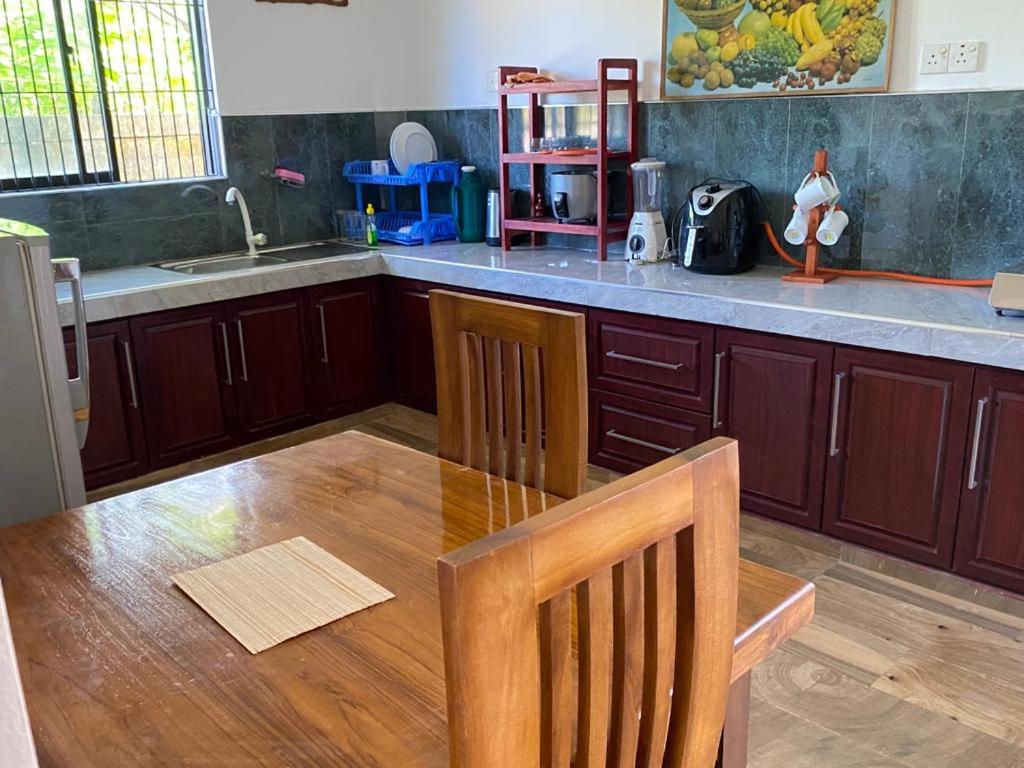 a kitchen with a wooden table and a counter top at White Villa in Weligama