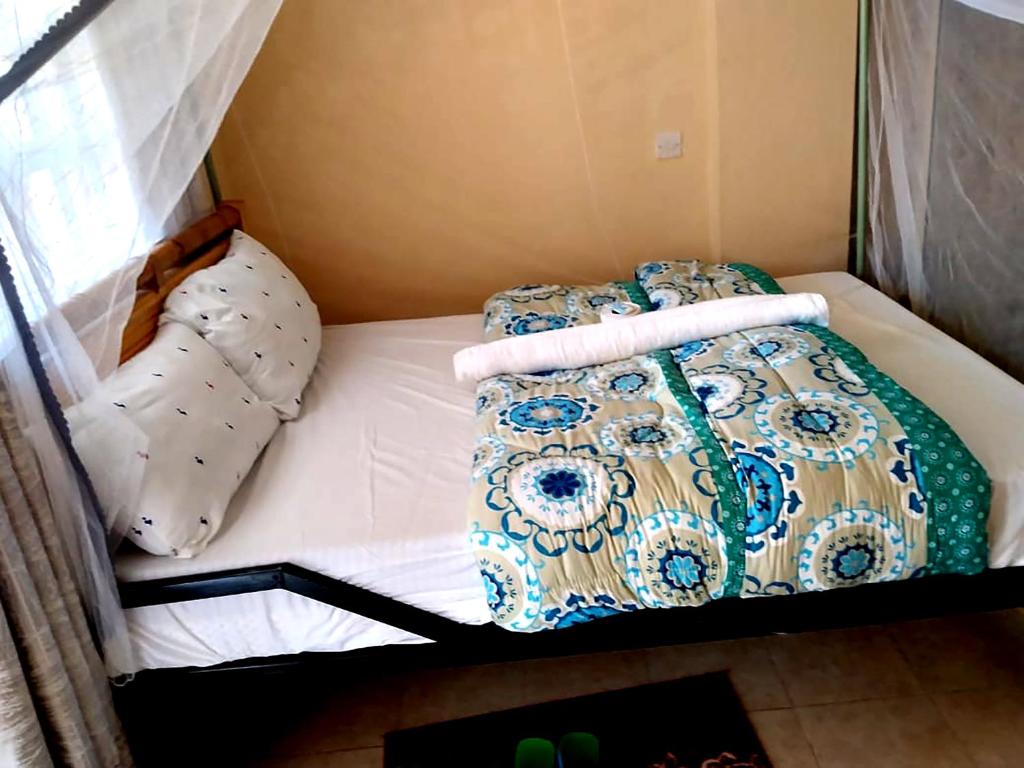een klein bed met 2 kussens en een deken bij VILLA DE LEO in Bungoma