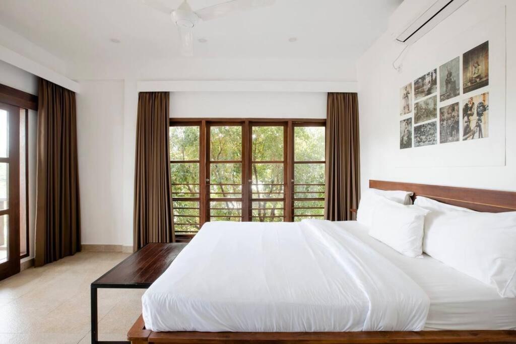 a white bedroom with a large bed and a window at Suite by the Sea Apartment Seminyak in Seminyak