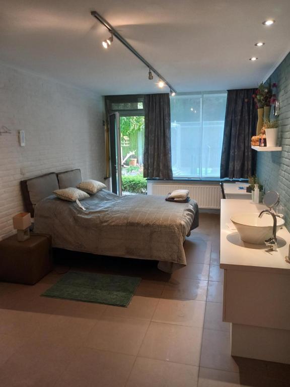 1 dormitorio con 1 cama y baño con lavamanos en Meerdaal Vakantie Studio en Haasrode
