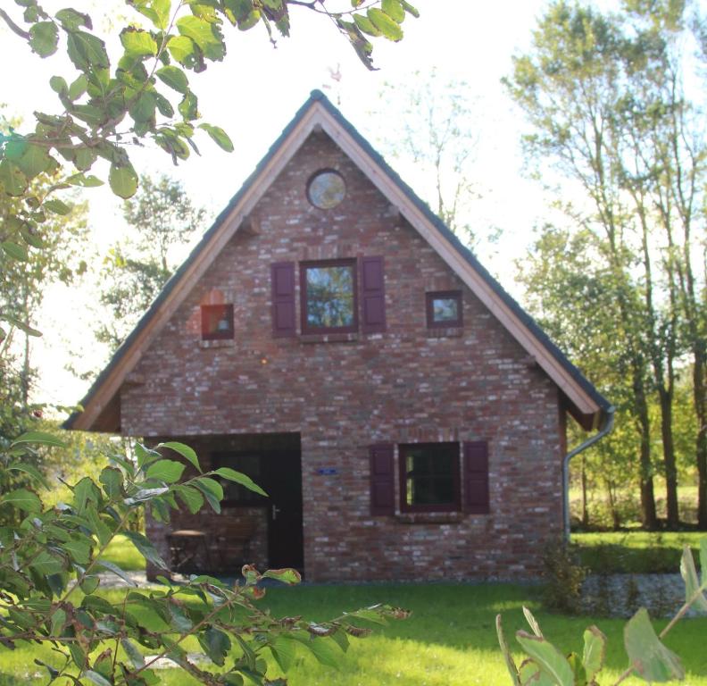 uma casa de tijolos com janelas roxas num quintal em Ferienhaus Luv em Pellworm