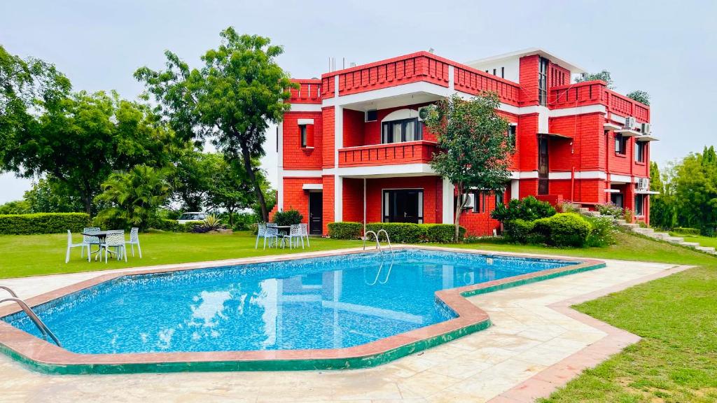 a house with a swimming pool in front of a building at Red orchid farm in Gurgaon
