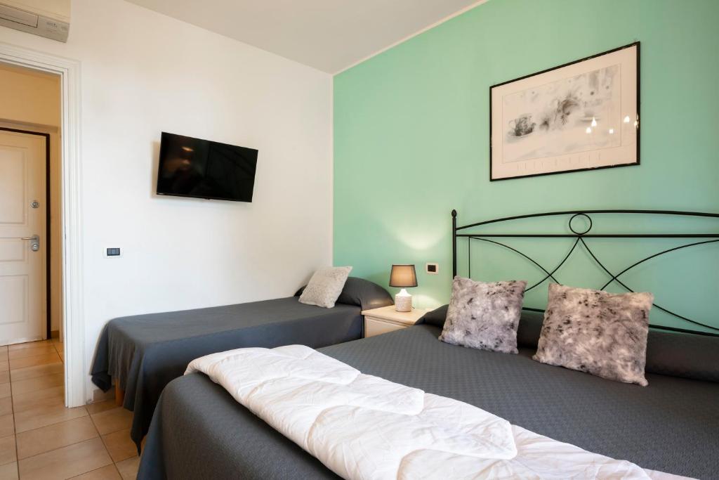 a bedroom with two beds and a flat screen tv at Ombra Verde Residence e B&B in Follonica
