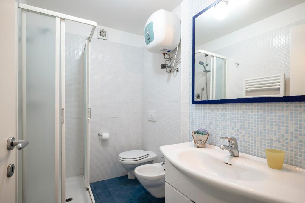 a bathroom with a sink and a toilet and a mirror at Ombra Verde Residence e B&B in Follonica