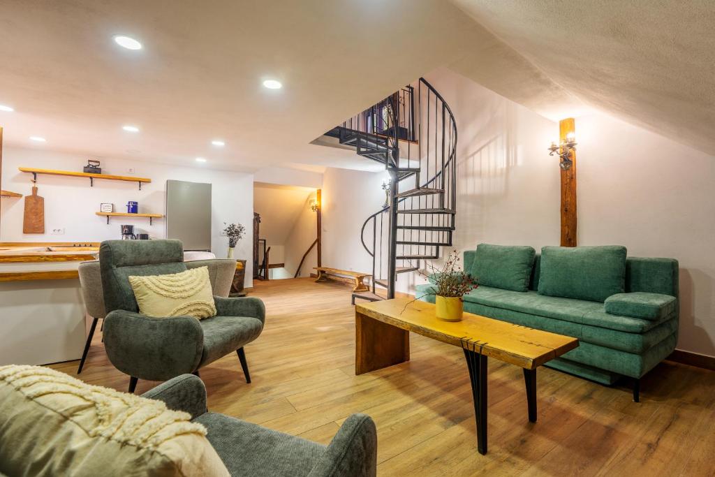 a living room with green furniture and a spiral staircase at Casa Maya Transilvania in Sighişoara