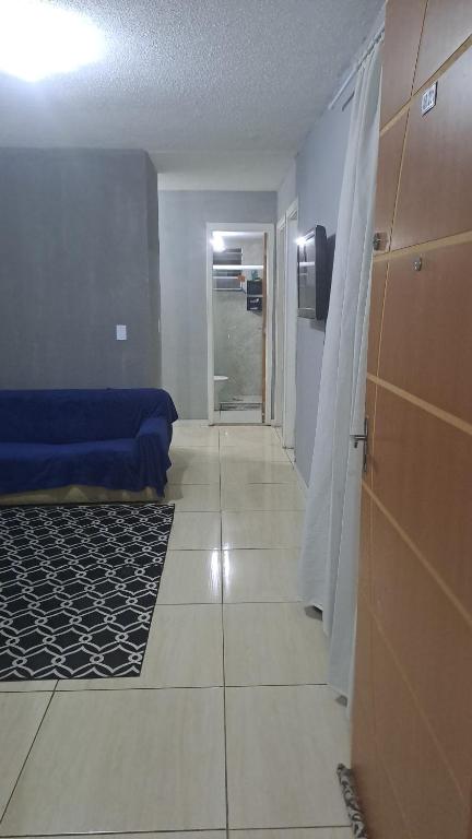 um quarto com uma cama azul e um corredor com uma porta em Família BRUMAR Condomio Dellos no Rio de Janeiro
