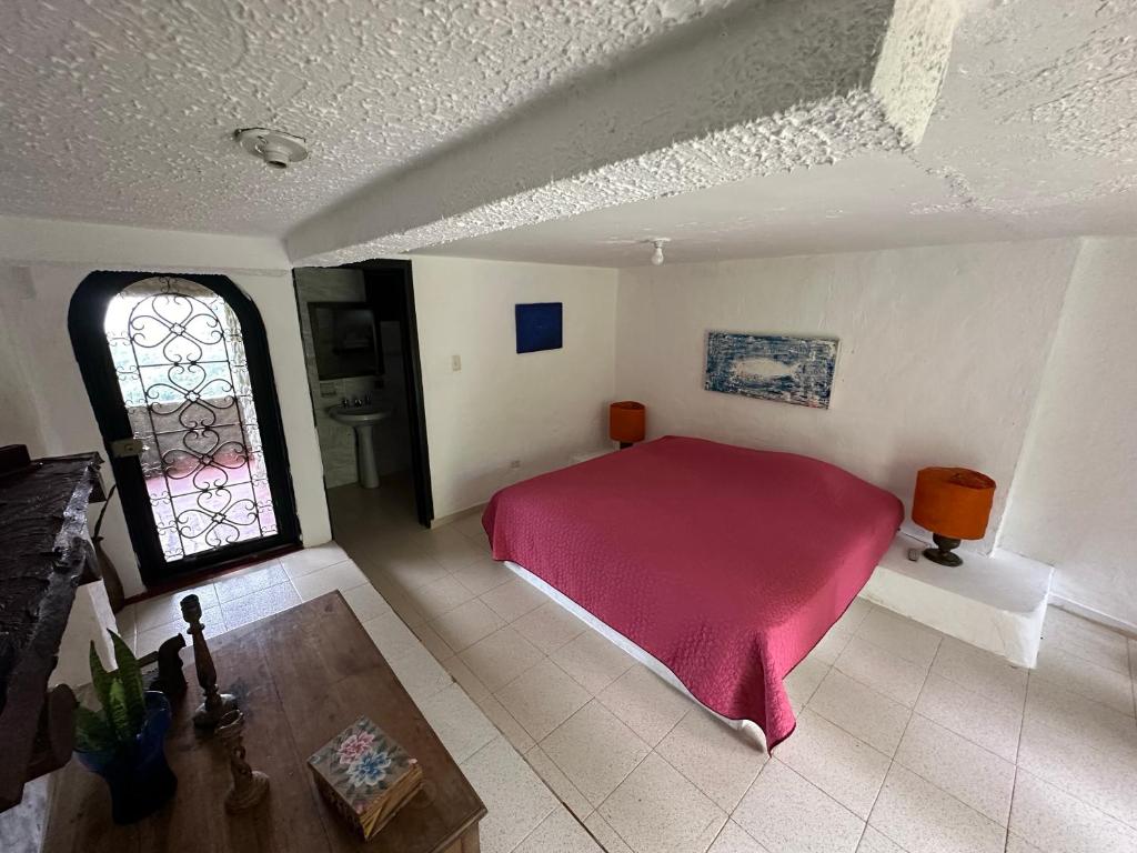 1 dormitorio con cama roja y ventana en Finca Jaragual, en La Vega