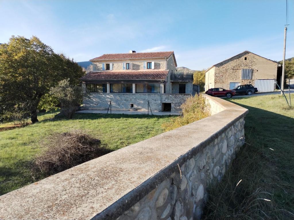 una casa con un muro di pietra di fronte a un cortile di Maison familiale de vacances a Serres