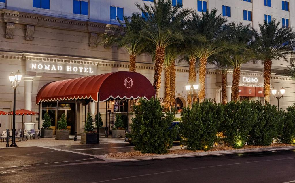 een hotel met palmbomen voor een gebouw bij NoMad Las Vegas in Las Vegas