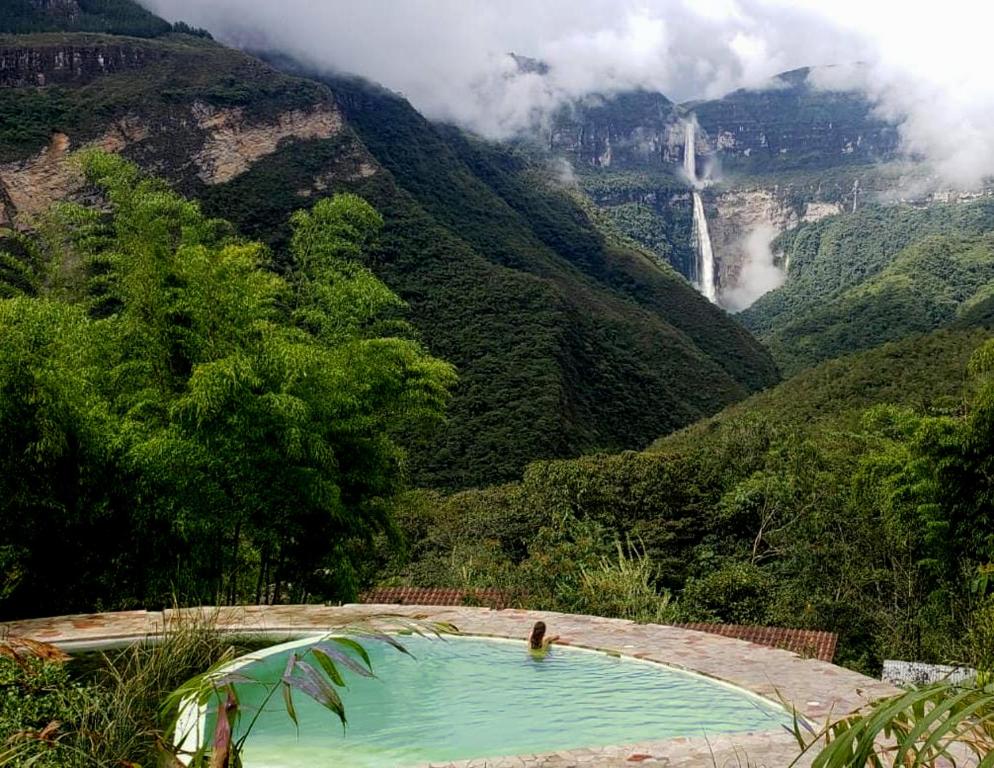 a person in a swimming pool in front of a waterfall at GoctaLab in Cocachimba