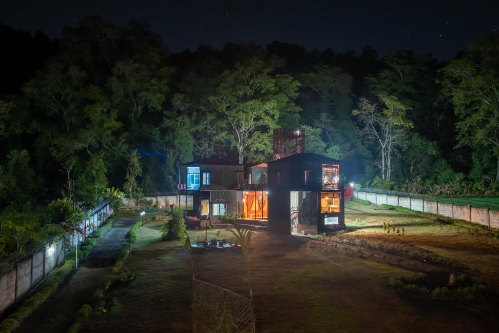 Una casa en el bosque por la noche en Shalom Corbett’s Hillside Hideaway, en Belparāo