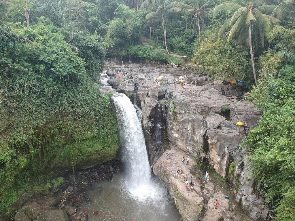 a waterfall in the middle of a river with people on it at Neny's Homestay in Saba
