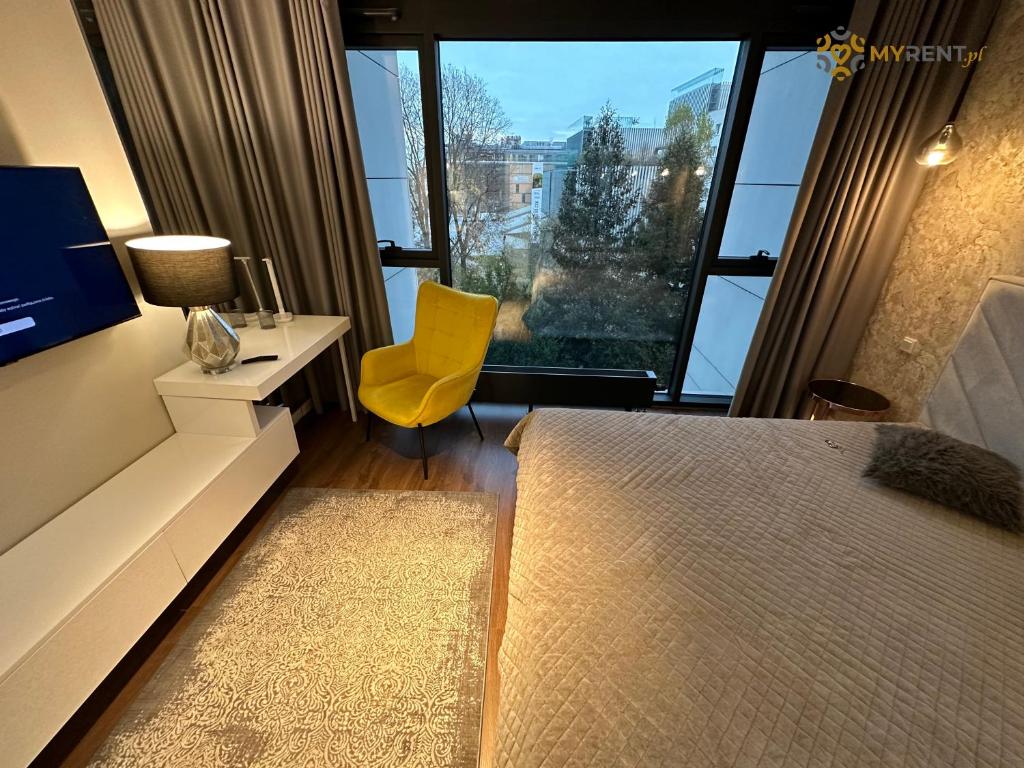 una camera con un letto, una sedia gialla e una finestra di UNIA ART Apartament 61 - BASEN, SPA a Lublino